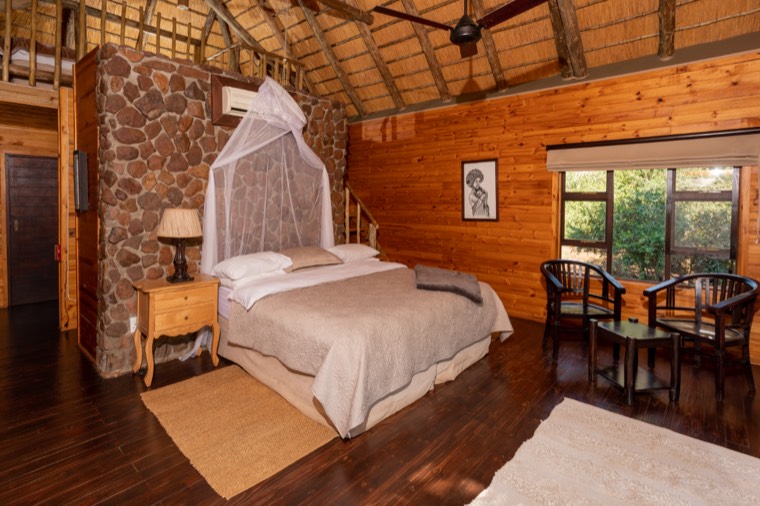 Double room with king bed, mosquito net and stone feature wall