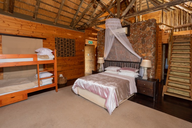 Family room with a double bed and bunk beds under a thatched roof