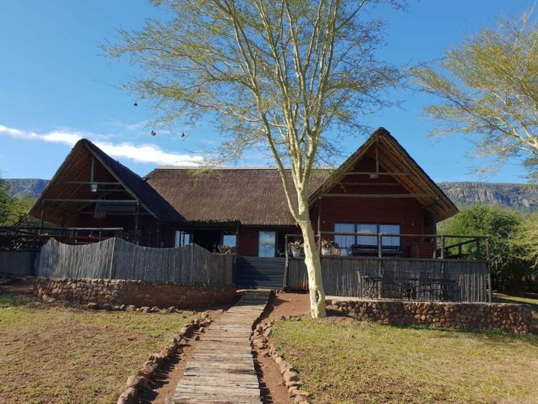 Kujabula Lodge's thatched main lodge and boardwalk, with the Lubombo Mountains behind